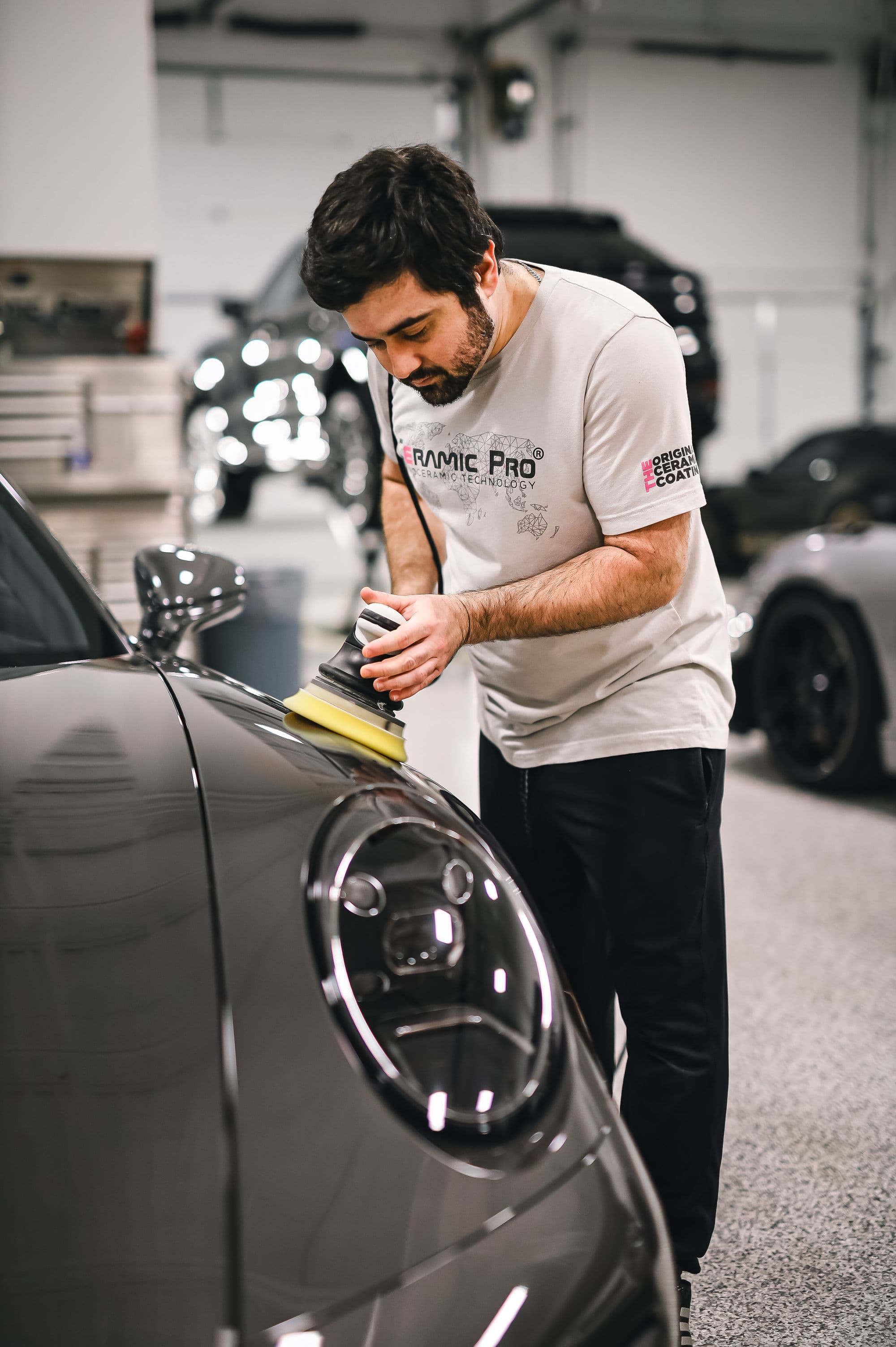 Detailer machine-polishing paint to a deep gloss in the shop