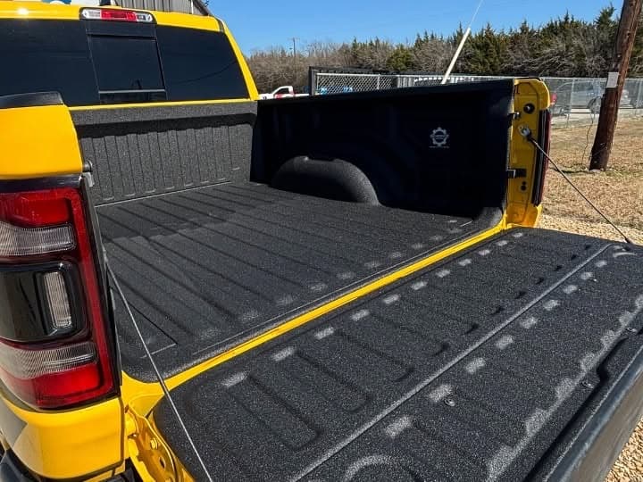 Fresh spray-in bedliner in a yellow Ram truck bed